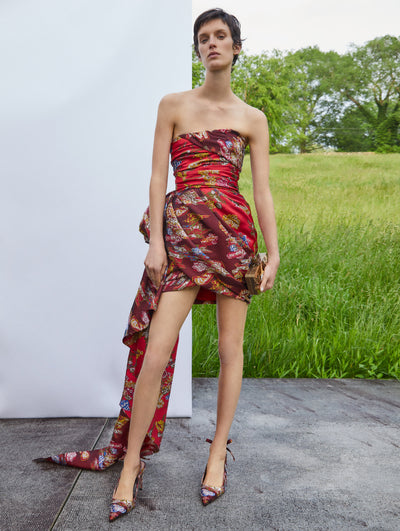 A model wears a cocktail dress with red and dark red multi print