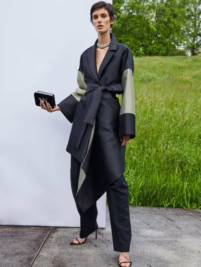 A model wears a black suit set with green on the sleeves
