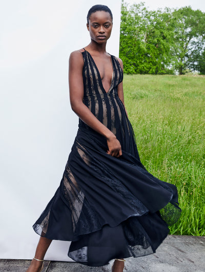 A model wears a black lace dress with low slit