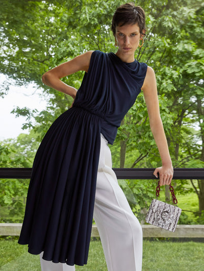 A model wears a black top white ruched details and white pants
