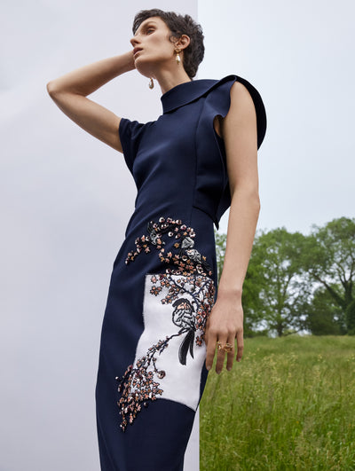 A model wears a navy dress with embroidered flowers and bird