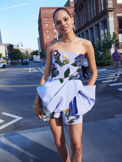 A model poses outside in an Oscar de la Renta blue floral embroidered cocktail dress.