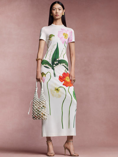 The model is wearing this short-sleeved gown, cut from ivory stretch wool, and adorned with oversized organza poppies in soft pinks, fiery reds and sunny yellows.