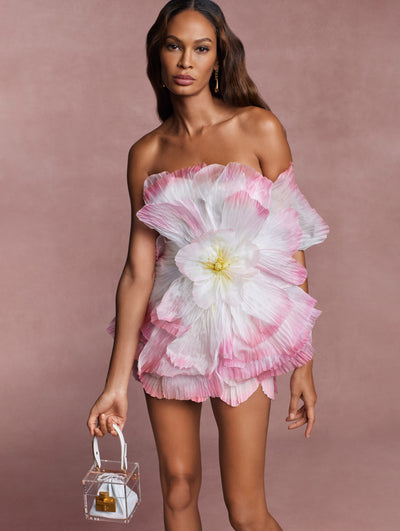 The model is wearing a statement cocktail dress, crafted from pleated organza and shaped into petals that wrap its leg-baring silhouette.