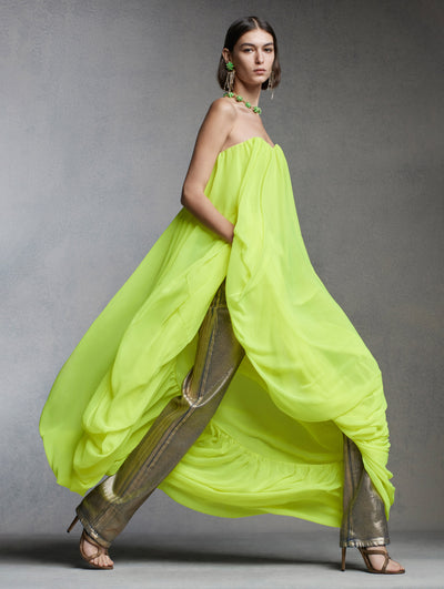 The model is wearing a strapless dress and metallic pants. 
