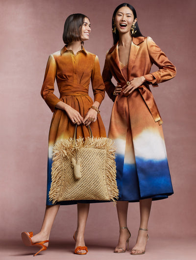 Two models are standing against a pink backdrop. The model on the left is wearing a long sleeved Abstract Ombre print dress and the model on the right is wearing the Abstract Ombre print coat. 