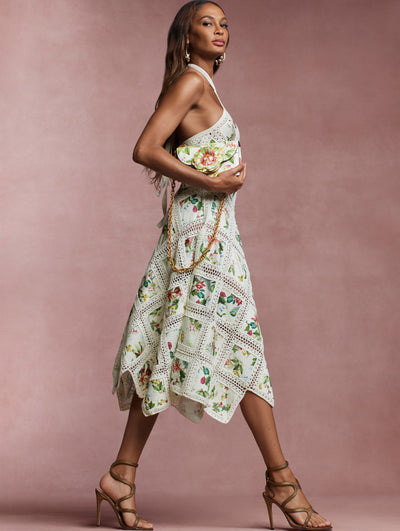 The model is wearing a halter neck knit dress with contrasting insets printed with the Flora & Fauna motif and a handkerchief hem. 