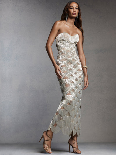 The model is wearing a strapless micro-chain gold cocktail dress. 