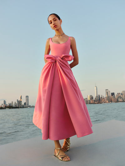 The model poses in a pink ankle length dress with a bow from Oscar de la Renta's Spring 2025 collection. 