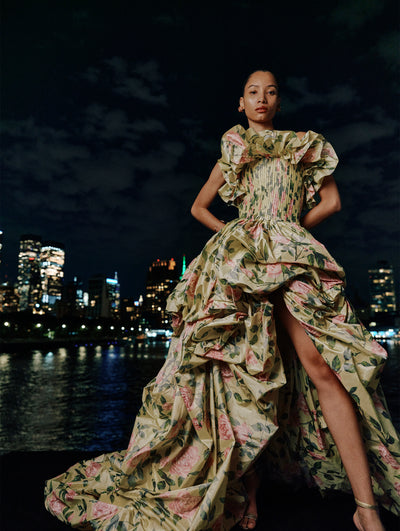 The model poses against the night skyline in a floor length floral gown from Oscar de la Renta's Spring 2025 collection. 