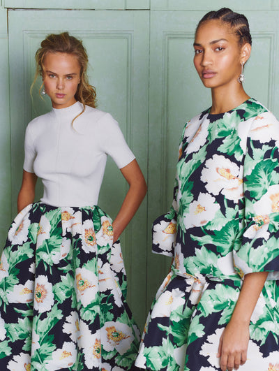 Two models; the model on the left wears a white skirt with a white flower printed skirt and the model on the right wears the same print in dress form