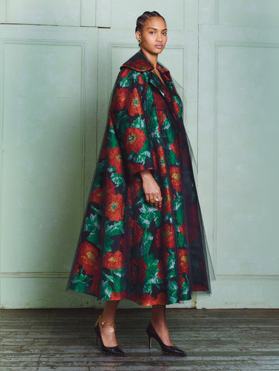 A model wears a tulle coat with red flowers