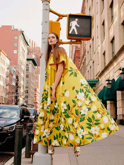 A model poses on a street pole in an Oscar de la Renta floral cotton poplin caftan. 