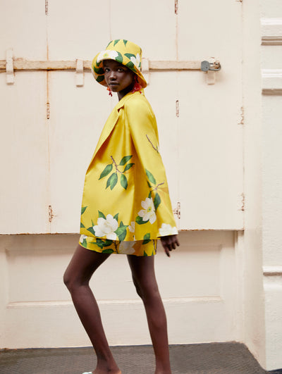 A model poses in an Oscar de la Renta yellow floral hat, jacket and short. 