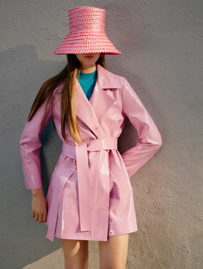 A model poses against a walk in an Oscar de la Renta pink jacket paired with a pink raffia hat. 
