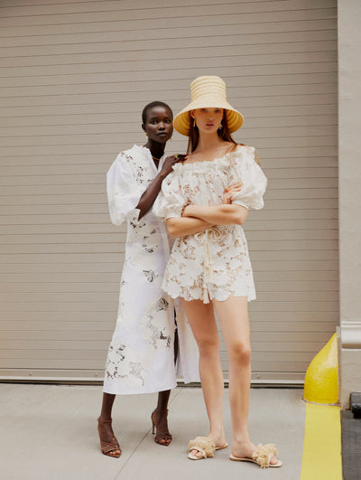 Two models pose on the New York City sidewalk wearing Oscar de la Renta white lace and cotton poplin ready-to-wear styles. 