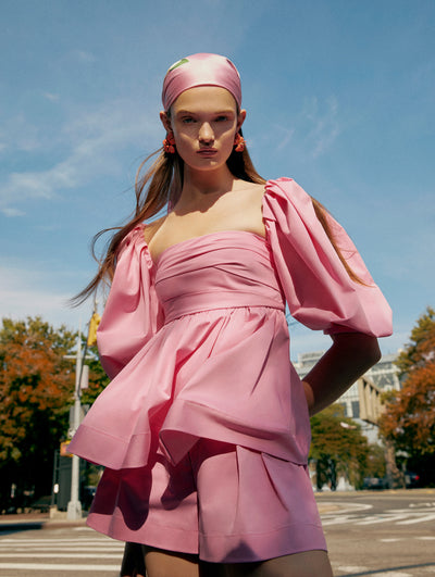 A model poses outside in an Oscar de la Renta pink blouse and short set. 