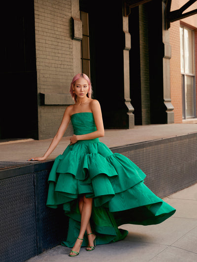 A model poses against a ledge in a green ruffle Oscar de la Renta gown. 