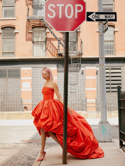 A model poses on the New York City sidewalk in an Oscar de la Renta red gown. 