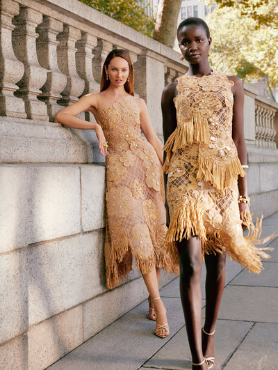 Two models pose outside of Bryant Park in New York City wearing Oscar de la Renta crochet dresses. 