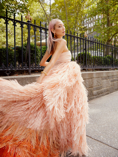A model is seen running on the sidewalk in an Oscar de la Renta pink ombre fringe gown. 