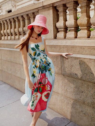 A model poses in an Oscar de la Renta floral cotton poplin day dress paired with a pink raffia hat. 