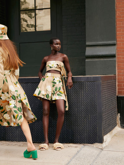 A model poses against a ledge wearing an Oscar de la Renta printed crop top and matching shorts. 