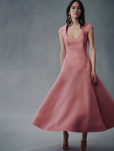 The model is wearing a light pink short sleeve long dress with a low U neck from Fall 2021.