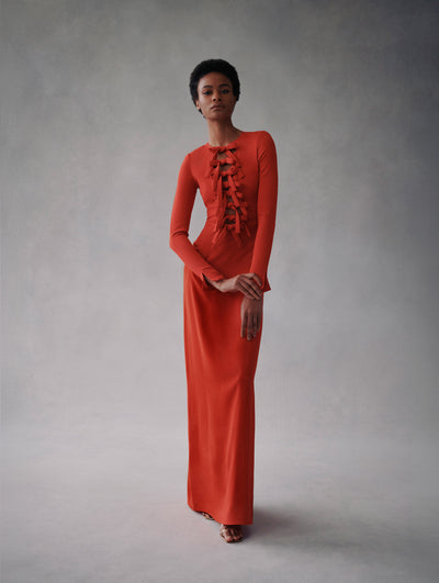 The model is wearing a red long sleeve maxi dress with a deep cut with bow details around the top from Fall 2021.