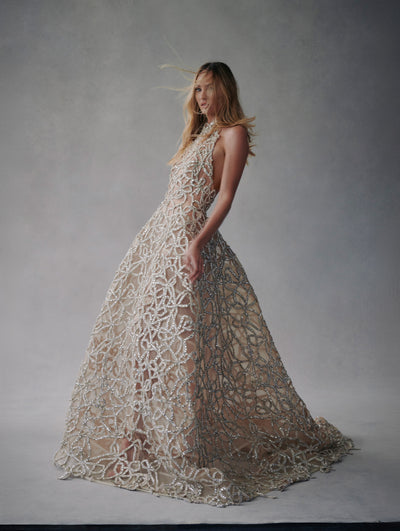 The model wears a halter crystal embellished gown from the Fall 2021 collection