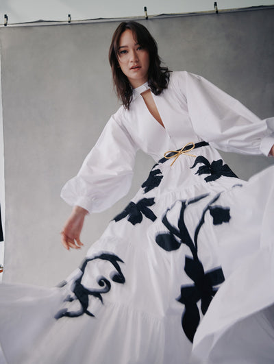 The model wears a white cotton poplin dress with puff sleeves and black embroidery in the skirt from fall 2021.