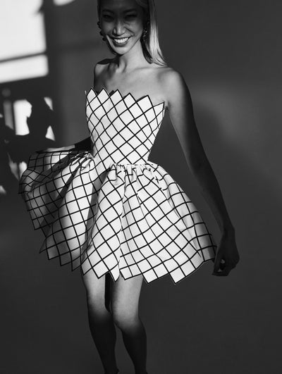 A model wears a white cocktail dress with black lattice detailing