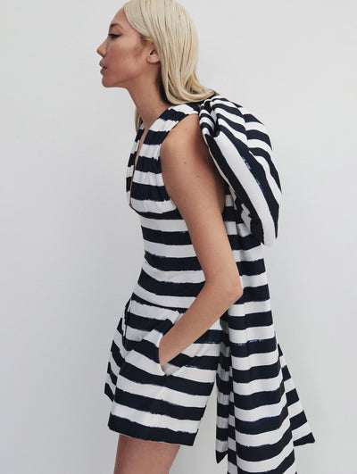 A model wears a navy and white striped pantsuit with a big bow on the back
