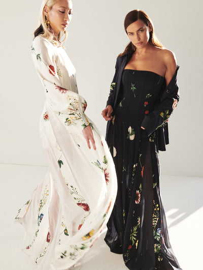 Two models shown; on the left the model wear a long white gown with printed flowers on the right the model wears a long black gown with printed flowers