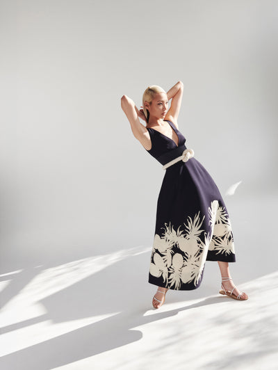 A model wears a navy dress with white pineapples embroidered on the bottom