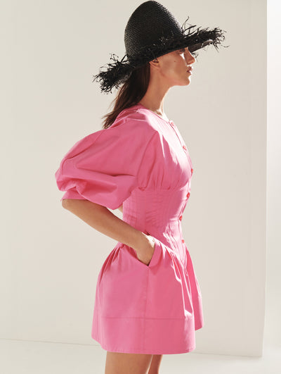 A model wears a pink dress with black straw hat