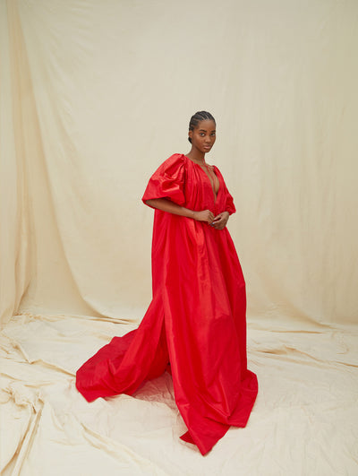 A model wears a long red gown with a slit in the middle chest area