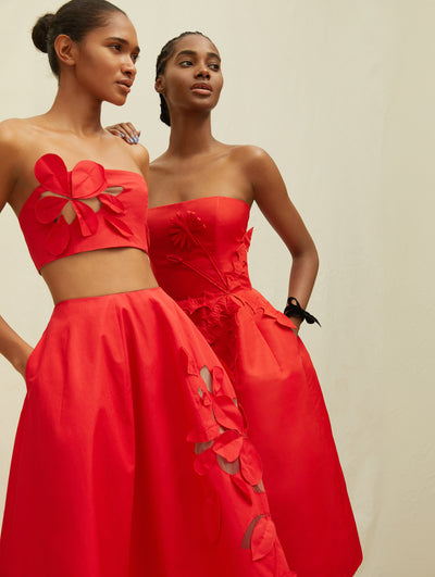 Two models wear red garments with embroidered flowers