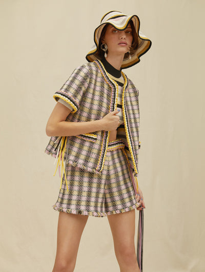A model wears a tweed short set with matching sweater and bucket hat