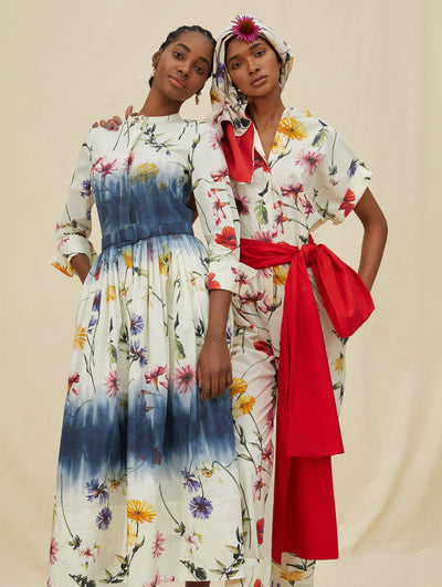 Two models wear white garments with a colorful flower print