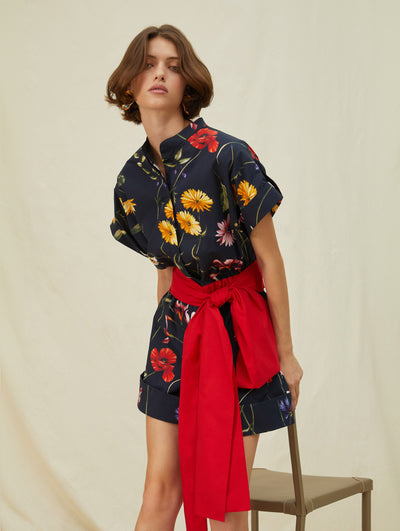A model wears a short black romper with colorful flowers printed