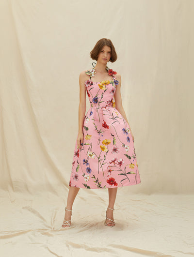 A model wears a pink cocktail dress with colorful flowers embroidered 