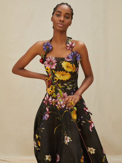 A model wears a long black gown with colorful flowers embroidered 