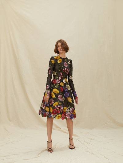 A model wears a black lace cocktail dress with colorful flowers embroidered 