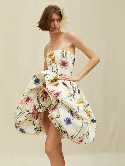 A model wears a short white dress with colorful rainbow flowers
