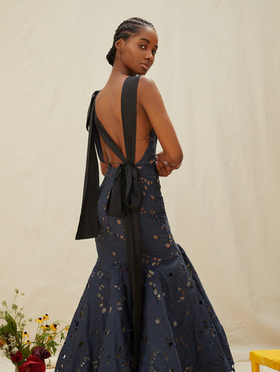 A model wears a navy gown with an open back and black bow