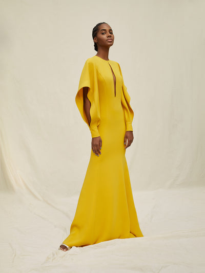 A model wears a yellow dress with puffy sleeves and a slit in the middle