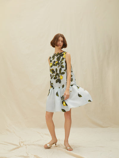 A model wears a short blue dress with lemons and vines