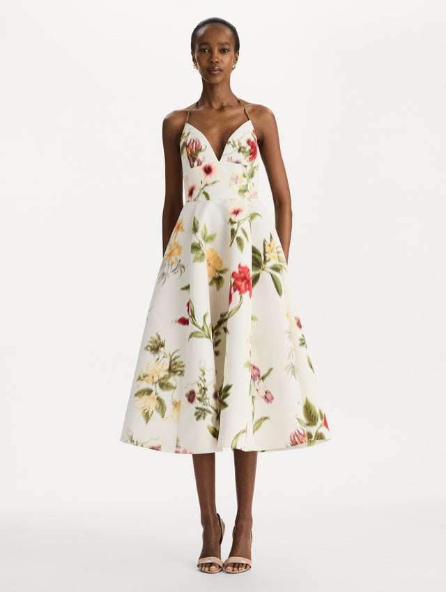 The model is wearing the Chiné Dominican Mixed-Floral Faille Cocktail Dress. Featuring a halter neckline, structured bodice, midi skirt, and belt at waist. Front View.