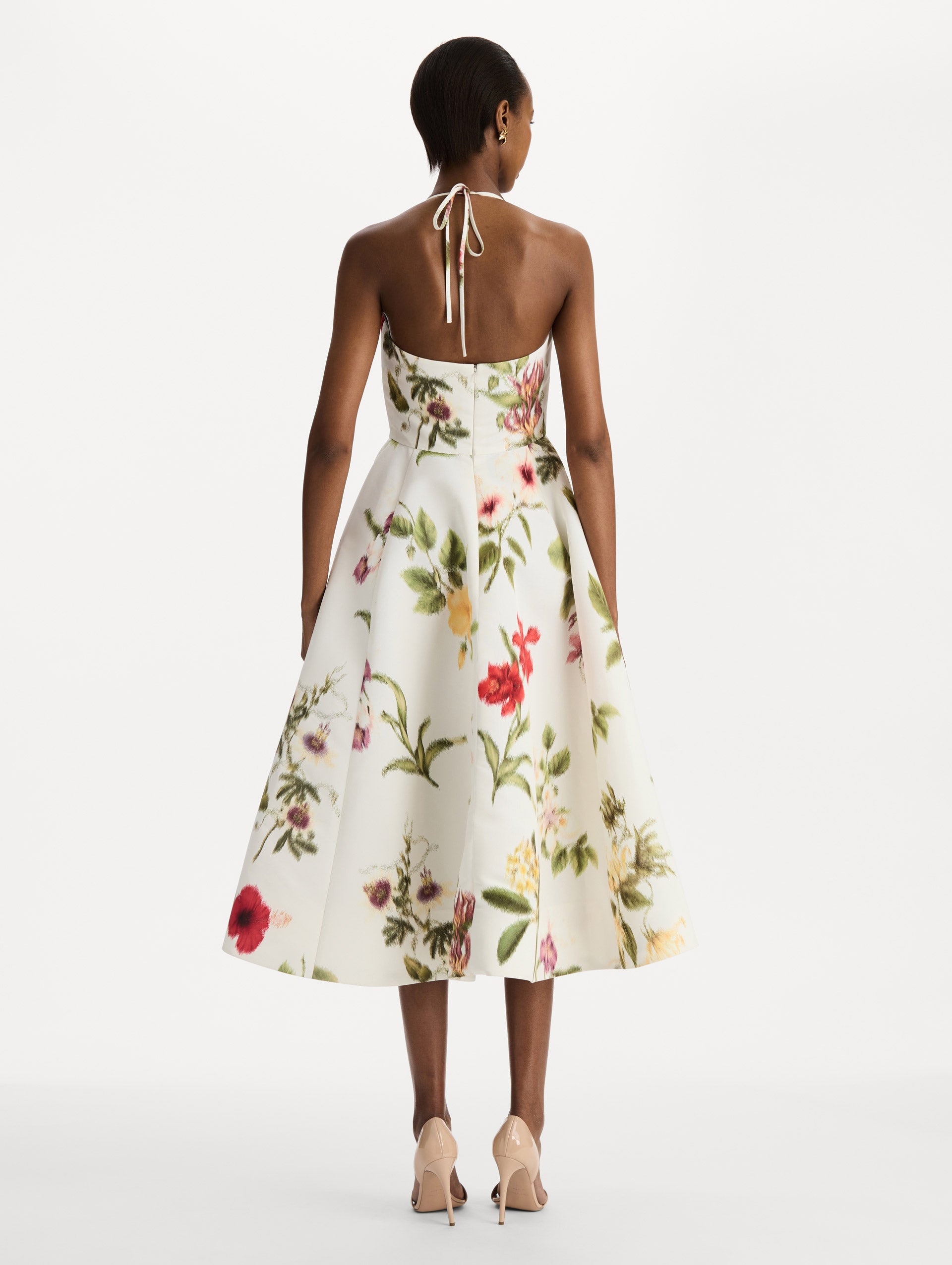 The model is wearing the Chiné Dominican Mixed-Floral Faille Cocktail Dress. Featuring a halter neckline, structured bodice, midi skirt, and belt at waist. Back View.